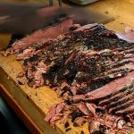 pastrami being sliced on a cutting board