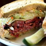 closeup off pastrami sandwich with a pickle