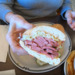 diner holding up a 4 inch thick pastrami sandwich